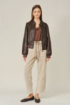 The Adeline Corduroy Trousers in dove, featuring a relaxed barrel-leg silhouette, textured corduroy fabric, and an eyelet waist with adjustable tie detail.