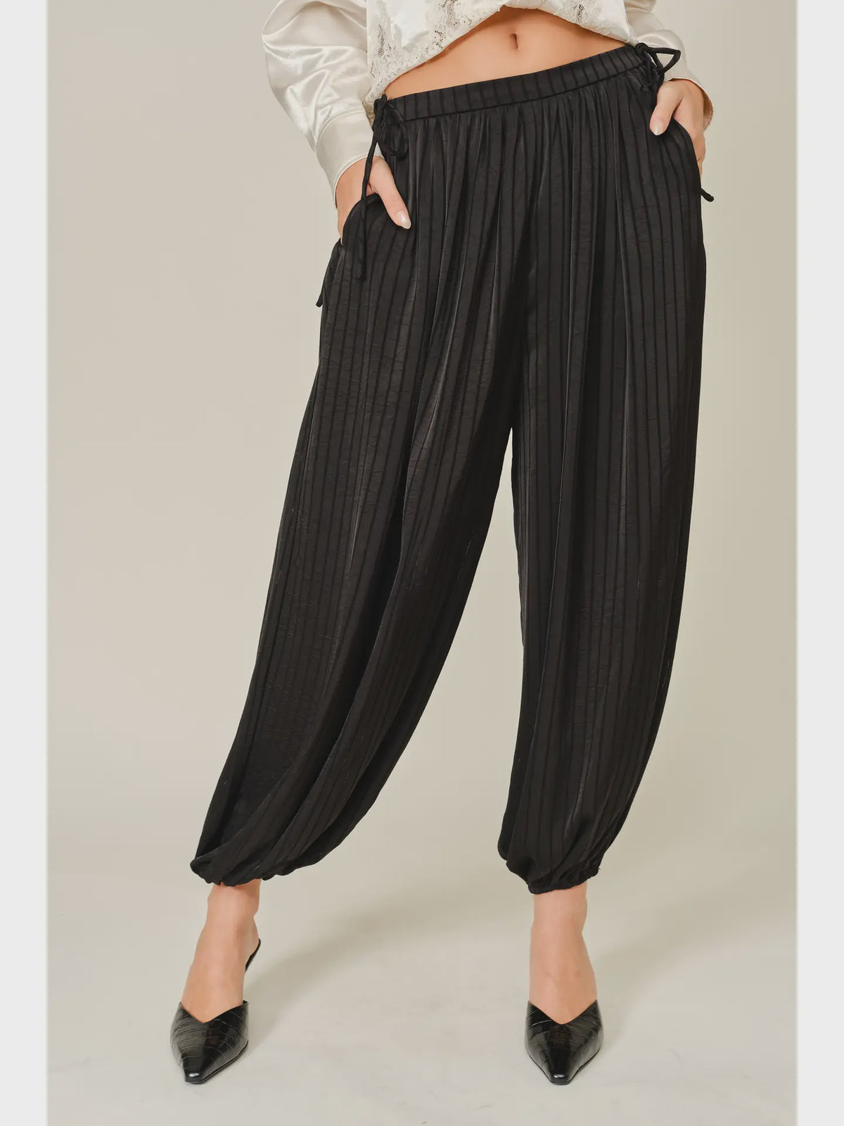 Zola Striped Satin Bubble Pants featuring a soft, glossy satin finish with a striped pattern, comfortable elastic waistband, adjustable drawstring side details, and functional side pockets. Designed with a relaxed, voluminous balloon silhouette and a flowy, lightweight feel for an effortlessly chic look.