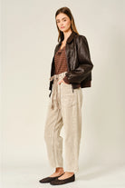 The Adeline Corduroy Trousers in dove, featuring a relaxed barrel-leg silhouette, textured corduroy fabric, and an eyelet waist with adjustable tie detail.