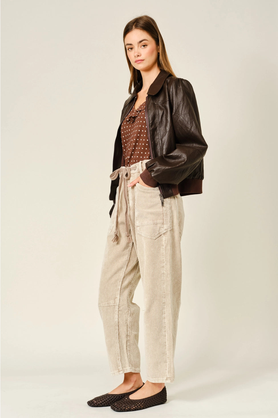 The Adeline Corduroy Trousers in dove, featuring a relaxed barrel-leg silhouette, textured corduroy fabric, and an eyelet waist with adjustable tie detail.