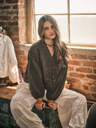 Women’s brown boho blouse featuring tonal floral embroidery, scalloped V-neckline, button-front closure, and relaxed long balloon sleeves.