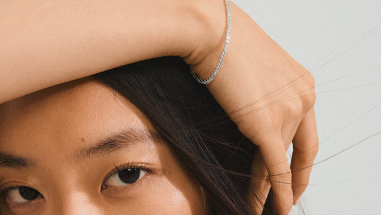Close-up of a person with a hand on their head, wearing a silver bracelet.
