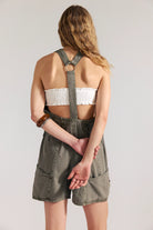 woman wearing a dark washed green romper with buttons at the front and with a v neck