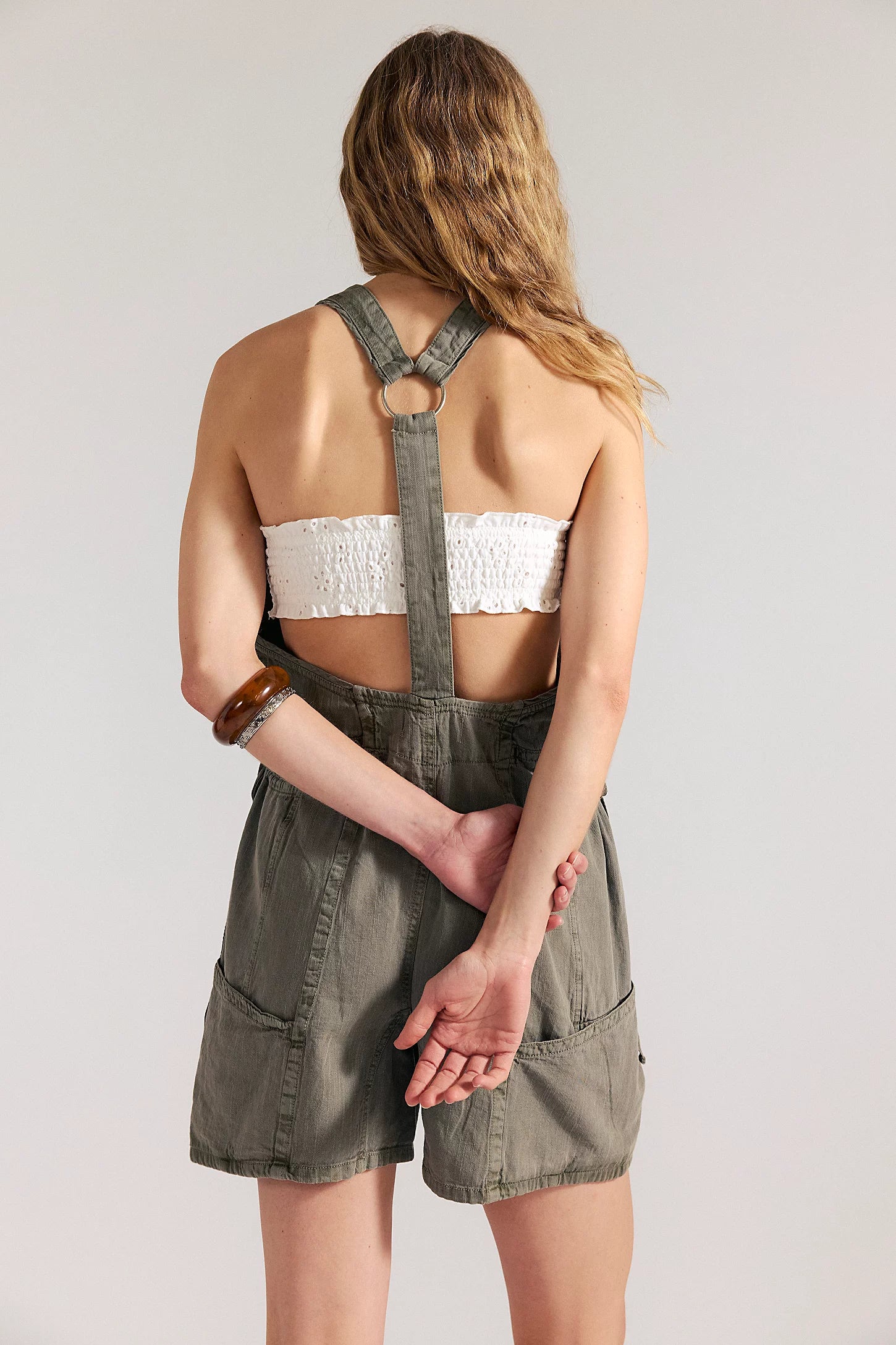 woman wearing a dark washed green romper with buttons at the front and with a v neck