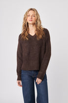 Woman wearing a brown sweater and blue jeans on a white background