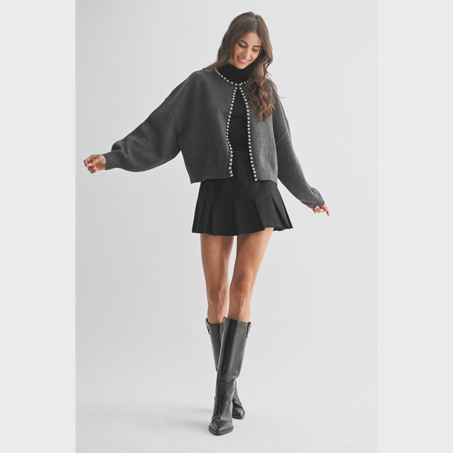 The Celeste Cardigan in a soft knit fabric, featuring delicate pearl detailing, a button-front design, and an elegant feminine silhouette.
