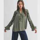 The Juliette Ruffle Blouse in olive green, featuring delicate ruffle detailing and a soft, silky finish.
