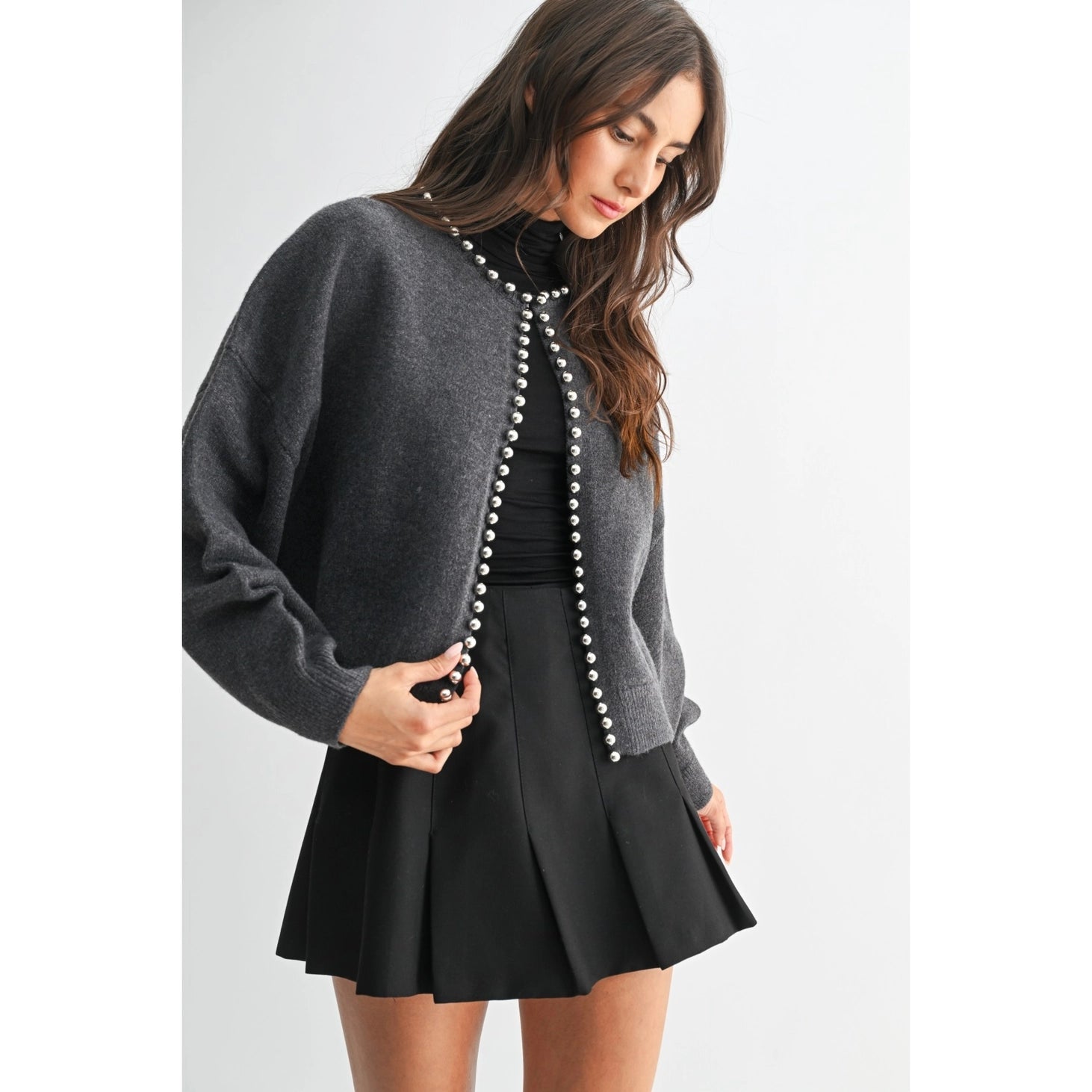 The Celeste Cardigan in a soft knit fabric, featuring delicate pearl detailing, a button-front design, and an elegant feminine silhouette.
