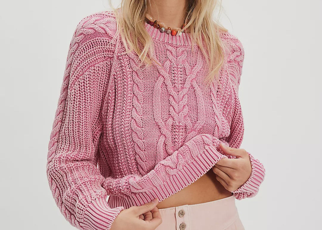 Woman wearing a pink knitted sweater and matching shorts on a white background