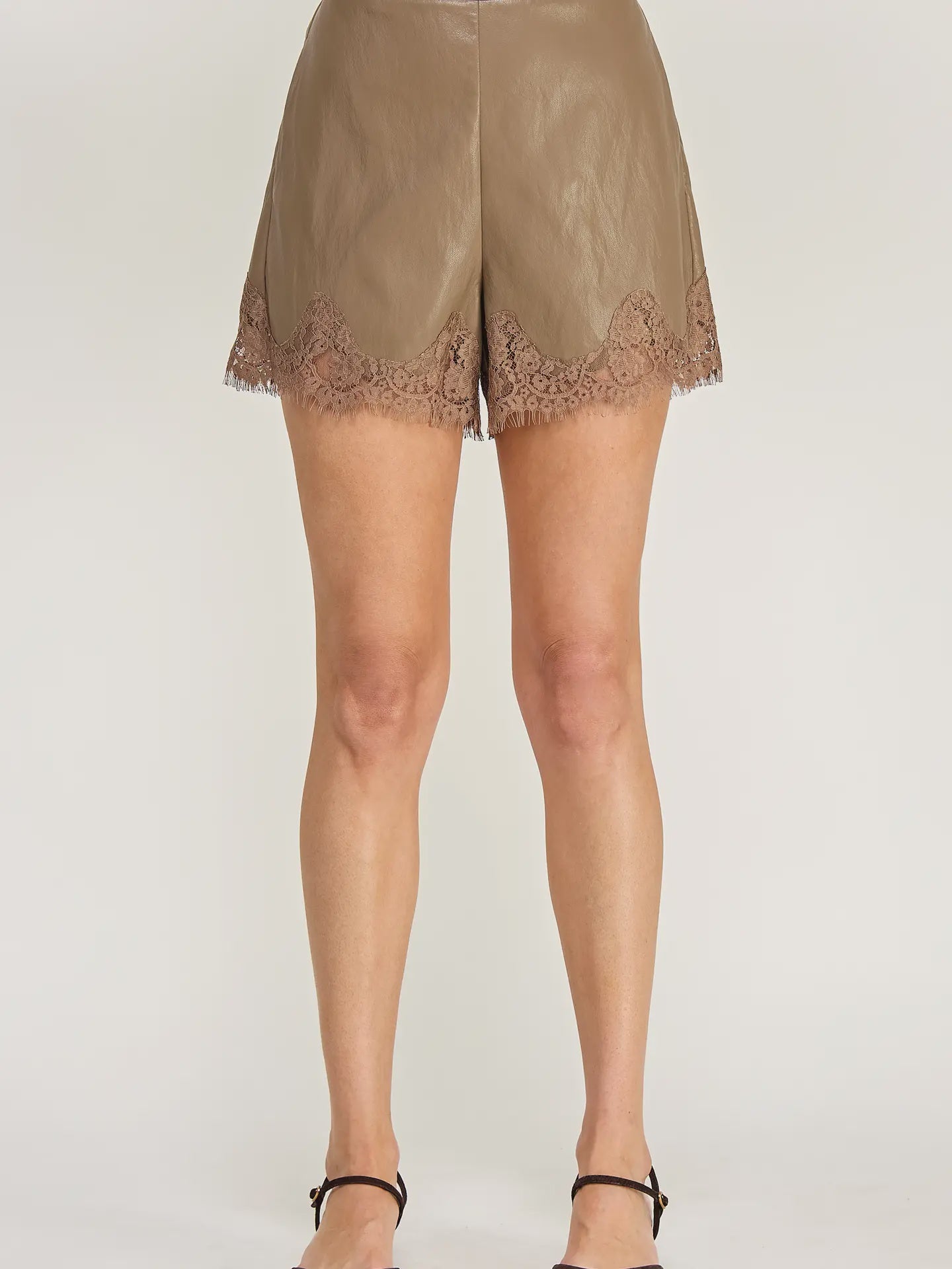 Clara Lace Trim Shorts featuring a smooth faux leather finish, flattering high-waisted silhouette, and delicate lace trim along the hem. Designed with a chic, feminine fit and edgy detailing. Pairs perfectly with the matching Clara Lace Trim Button-Down Top for a coordinated look.