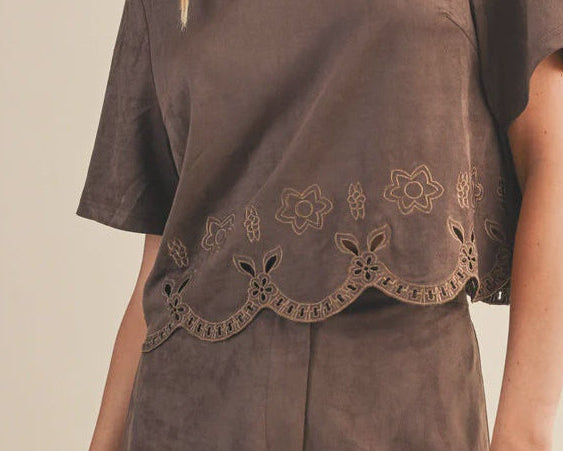 Woman wearing a brown outfit with lace details on a beige background