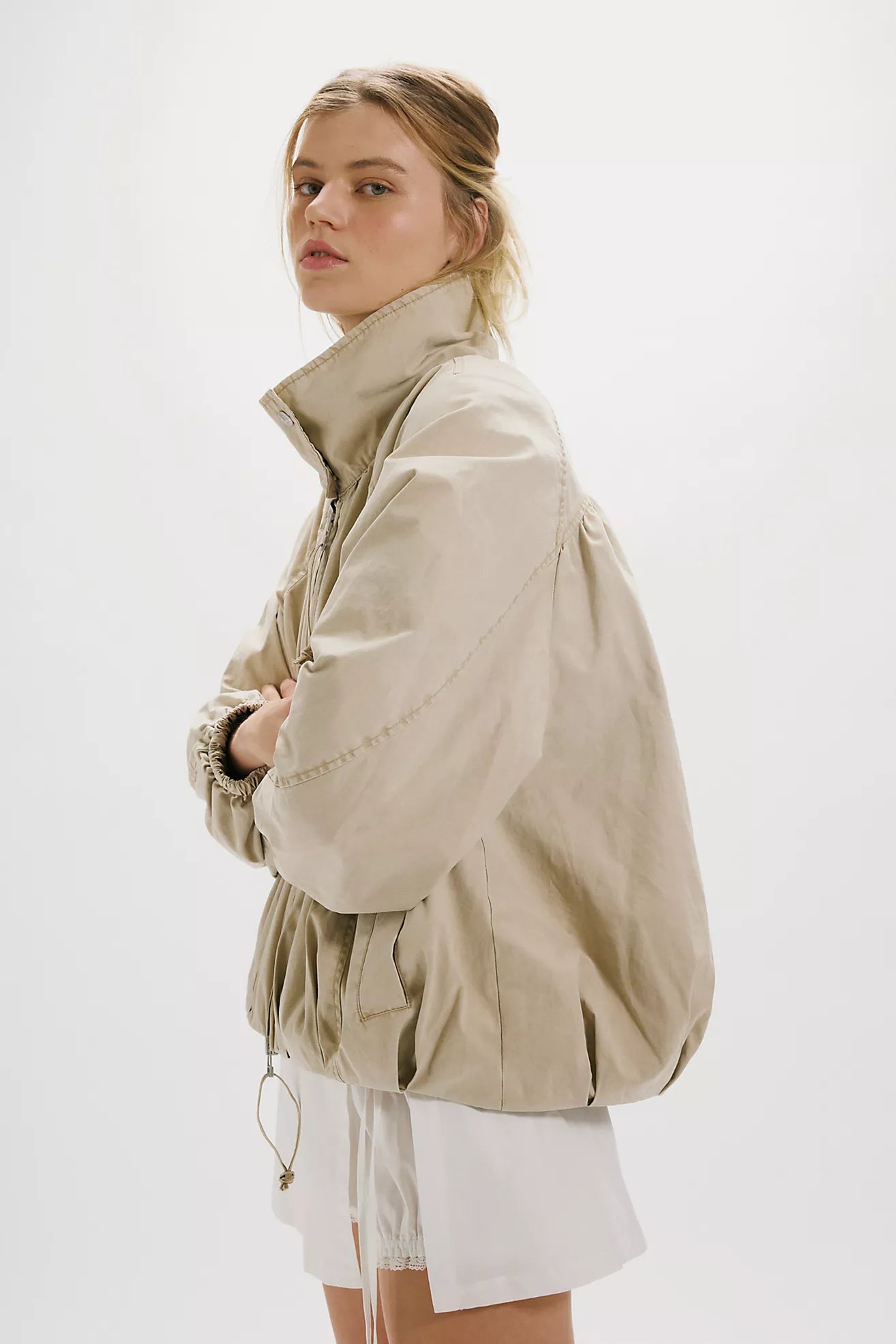 Free People Chelsea Funnel Neck Jacket in Oatmeal featuring an oversized slouchy fit, lightweight cotton-blend fabric, funnel-neck collar, raglan sleeves, adjustable drawcord waist, front zipper closure, and side slit pockets.