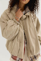Free People Chelsea Funnel Neck Jacket in Oatmeal featuring an oversized slouchy fit, lightweight cotton-blend fabric, funnel-neck collar, raglan sleeves, adjustable drawcord waist, front zipper closure, and side slit pockets.