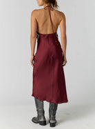 Satin midi dress with an adjustable halter neckline, fit-and-flare silhouette, handkerchief-style bodice, strapless design, and open back. Finished with a smooth satin fabrication and easy pull-on construction.