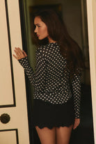 Fitted waffle-knit cardigan in a chocolate polka dot print with a crew neckline, long fitted sleeves, and snap-button front closure.