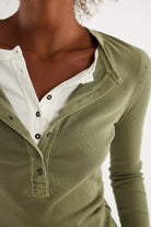 Woman wearing a green long-sleeve henley shirt with a half button down v neck