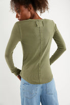 Woman wearing a green long-sleeve henley shirt with a half button down v neck