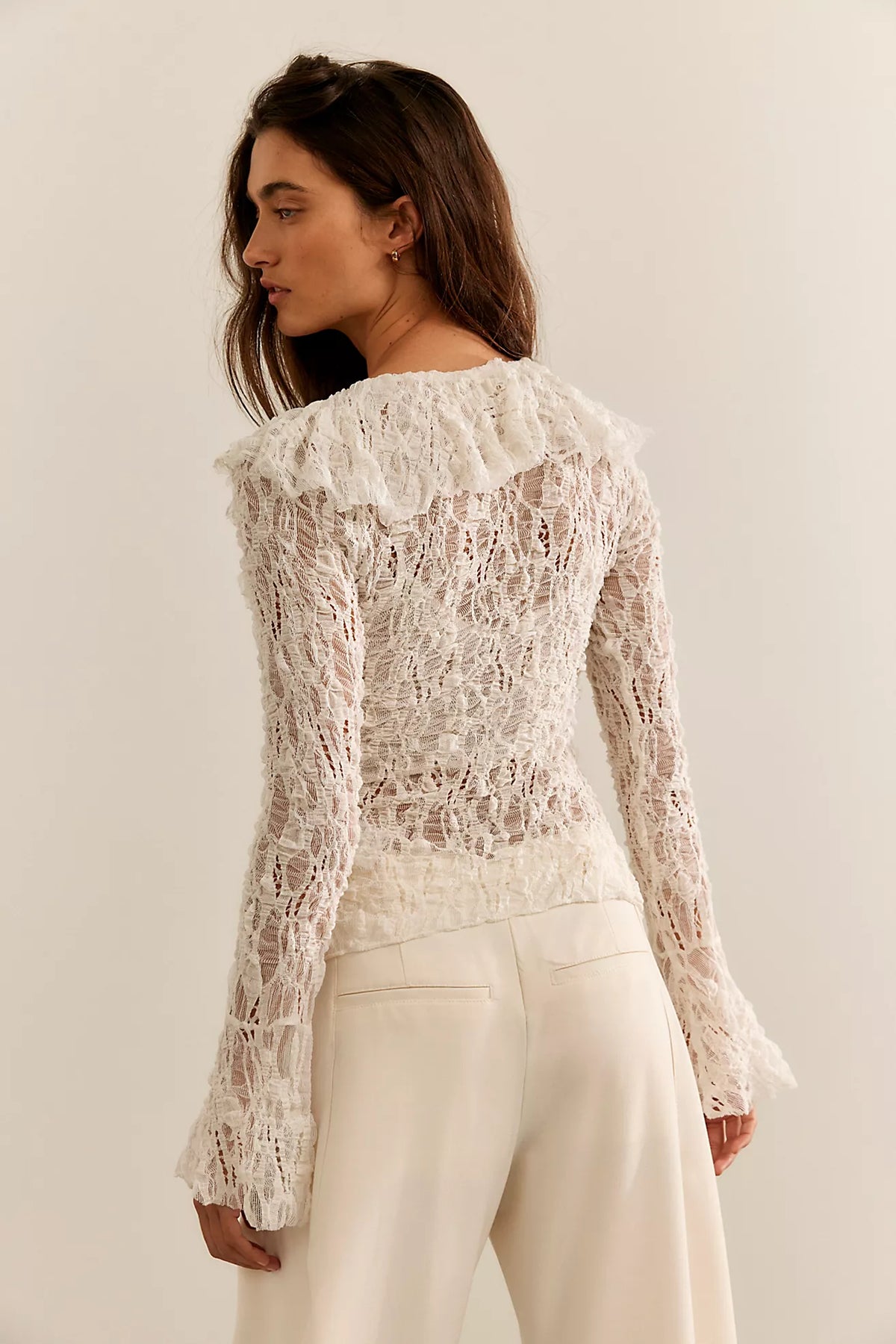 Textured lace cardigan in ivory, featuring a fitted longline silhouette, V-neckline, button-front closure, fitted long sleeves, and cascading ruffle hem detailing.