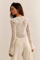 Textured lace cardigan in ivory, featuring a fitted longline silhouette, V-neckline, button-front closure, fitted long sleeves, and cascading ruffle hem detailing.