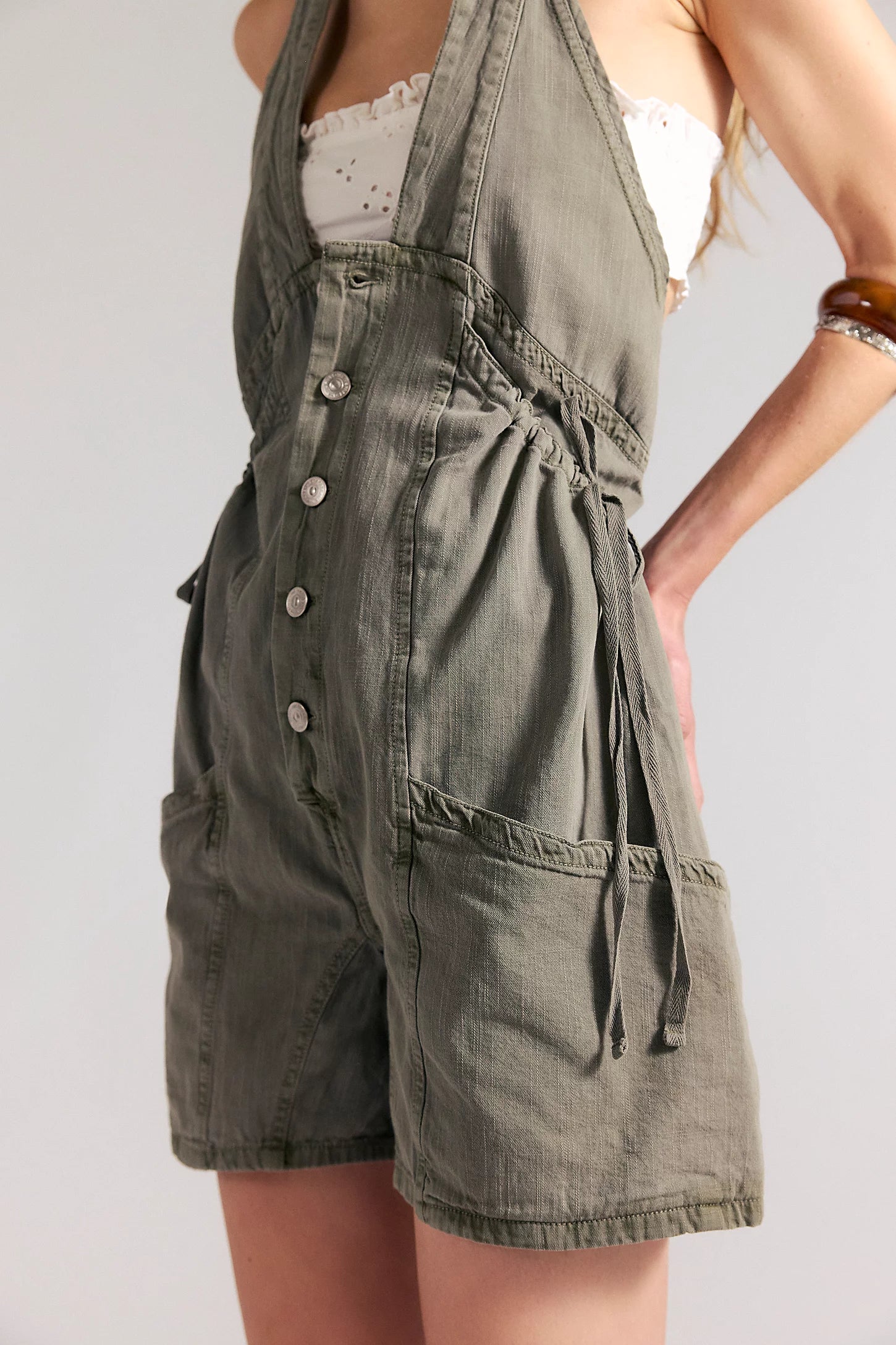 woman wearing a dark washed green romper with buttons at the front and with a v neck
