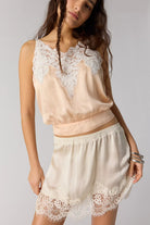 woman wearing satin a line mini skirt with a lace hem. Ivory / cream colour