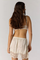woman wearing satin a line mini skirt with a lace hem. Ivory / cream colour