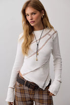 Fitted waffle-knit long-sleeve top with a crew neckline, delicate lace paneling, pointed hem, and lettuce-edge trim. Made from a soft cotton blend with added stretch.