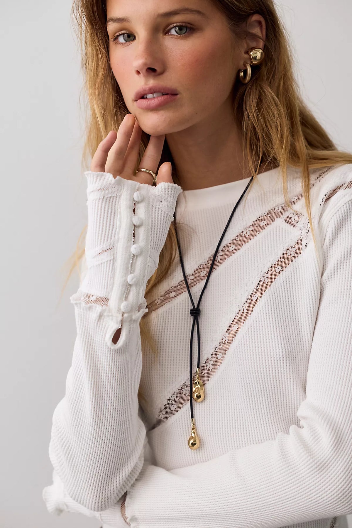 Fitted waffle-knit long-sleeve top with a crew neckline, delicate lace paneling, pointed hem, and lettuce-edge trim. Made from a soft cotton blend with added stretch.