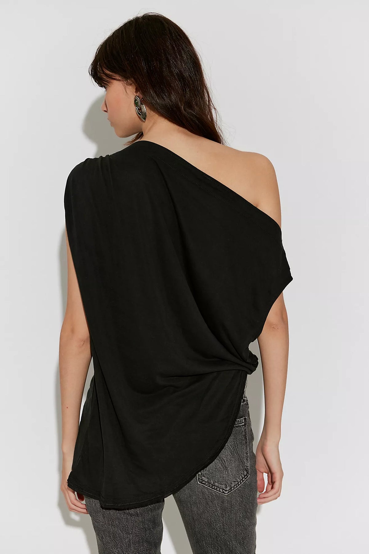 Cascadia Tunic in black featuring a draped off-the-shoulder neckline, soft slinky jersey fabric, ruched detailing, long sleeves, a relaxed longline silhouette, and an asymmetrical hem.