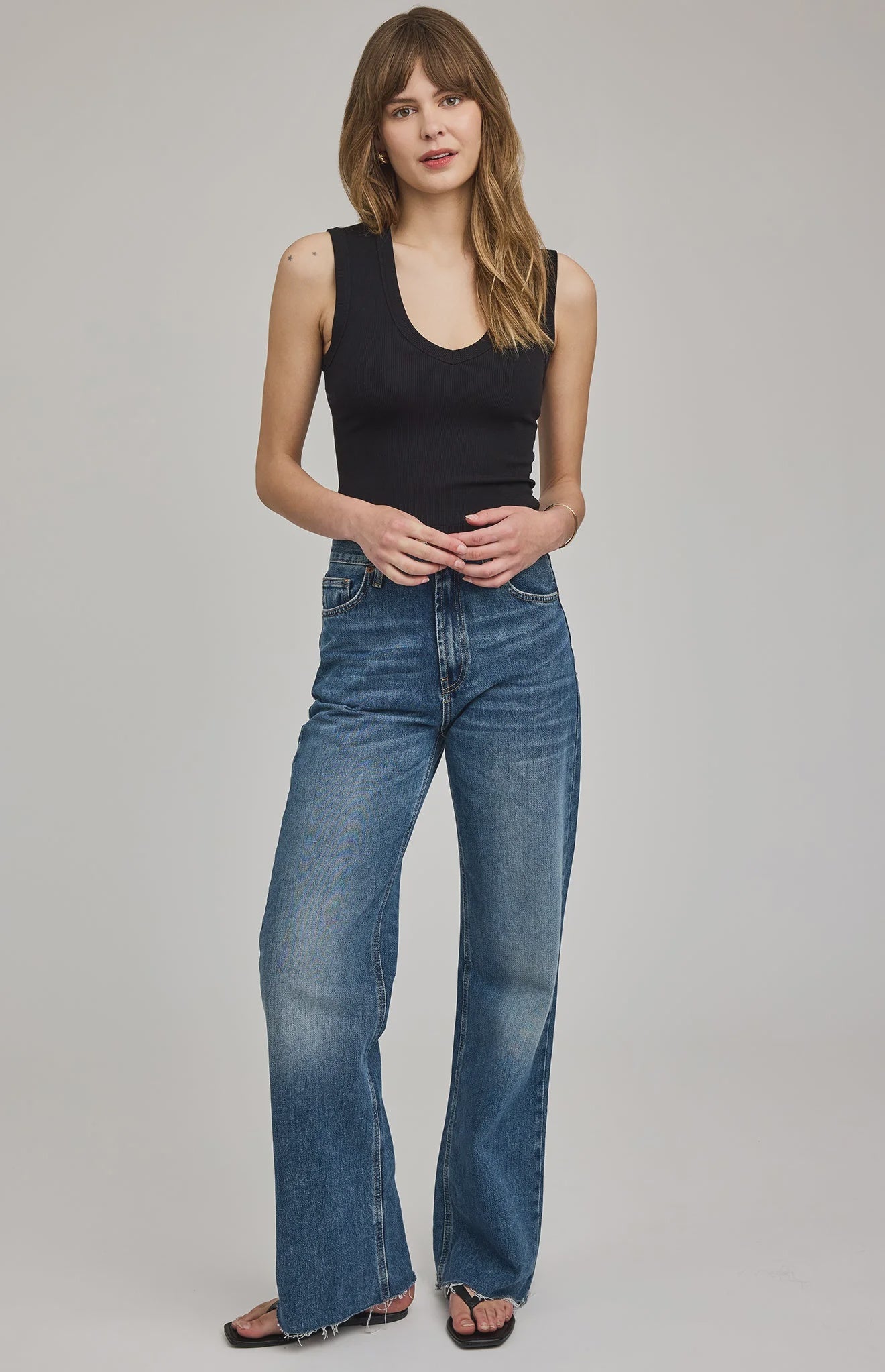 Women's black ribbed cropped tank top featuring a flattering V-neckline, wide straps, and a fitted silhouette in a soft stretch knit.