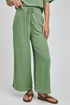 Person wearing green wide-leg pants on a white background
