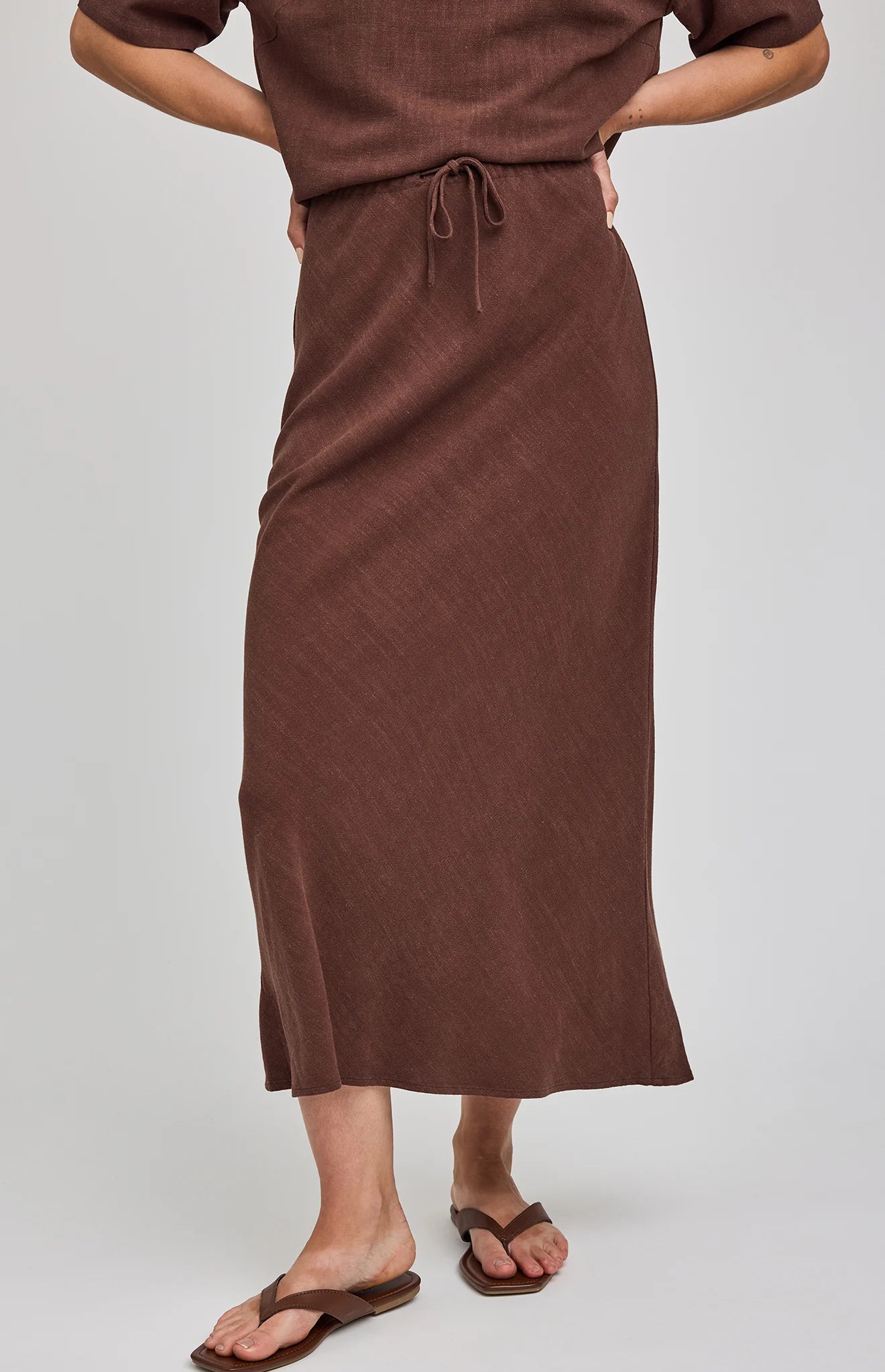 Bias-cut midi skirt in a lightweight rayon-linen blend featuring an adjustable drawstring waist for a customizable mid-rise or high-rise fit and a soft, flowing silhouette. Colour: Espresso