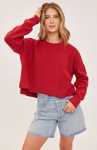 red oversized knit pullover sweater featuring a classic crew neckline, exposed seam detailing, side slits, and a soft textured half-cardigan stitch.