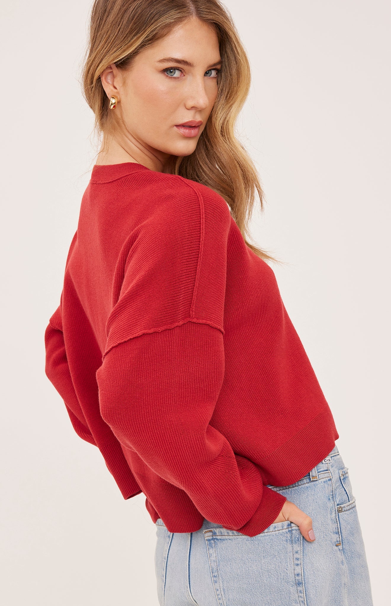 red oversized knit pullover sweater featuring a classic crew neckline, exposed seam detailing, side slits, and a soft textured half-cardigan stitch.
