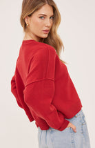 red oversized knit pullover sweater featuring a classic crew neckline, exposed seam detailing, side slits, and a soft textured half-cardigan stitch.