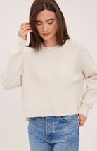 Women's cream oversized knit pullover sweater featuring a classic crew neckline, exposed seam detailing, side slits, and a soft textured half-cardigan stitch.