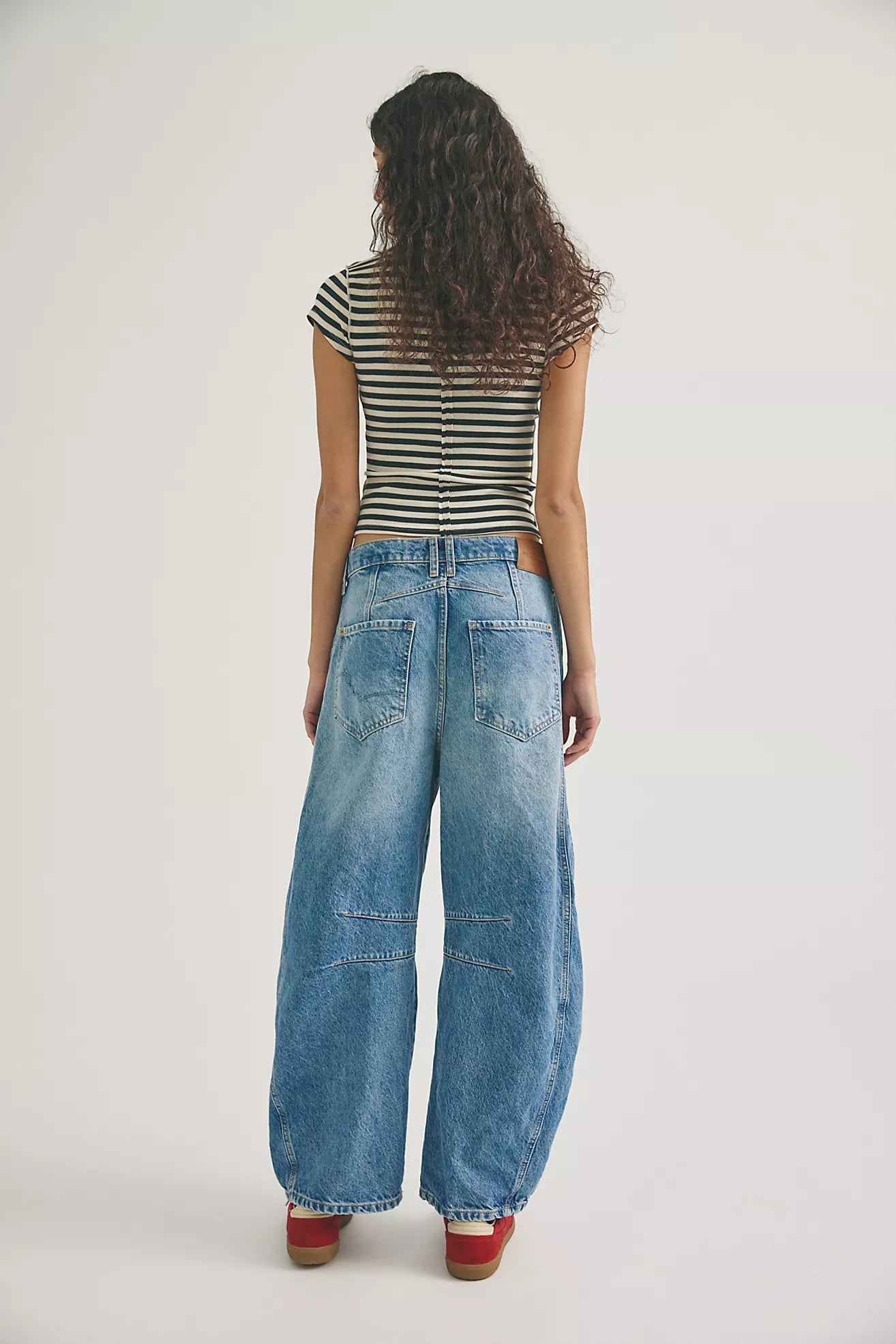 woman wearing mid rise barrel jeans in a mid wash. ankle length