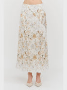Harper Floral Midi Skirt in soft yellow and cream featuring a delicate floral print, smooth satin finish, white lace panel detailing, and a flowing midi-length silhouette.