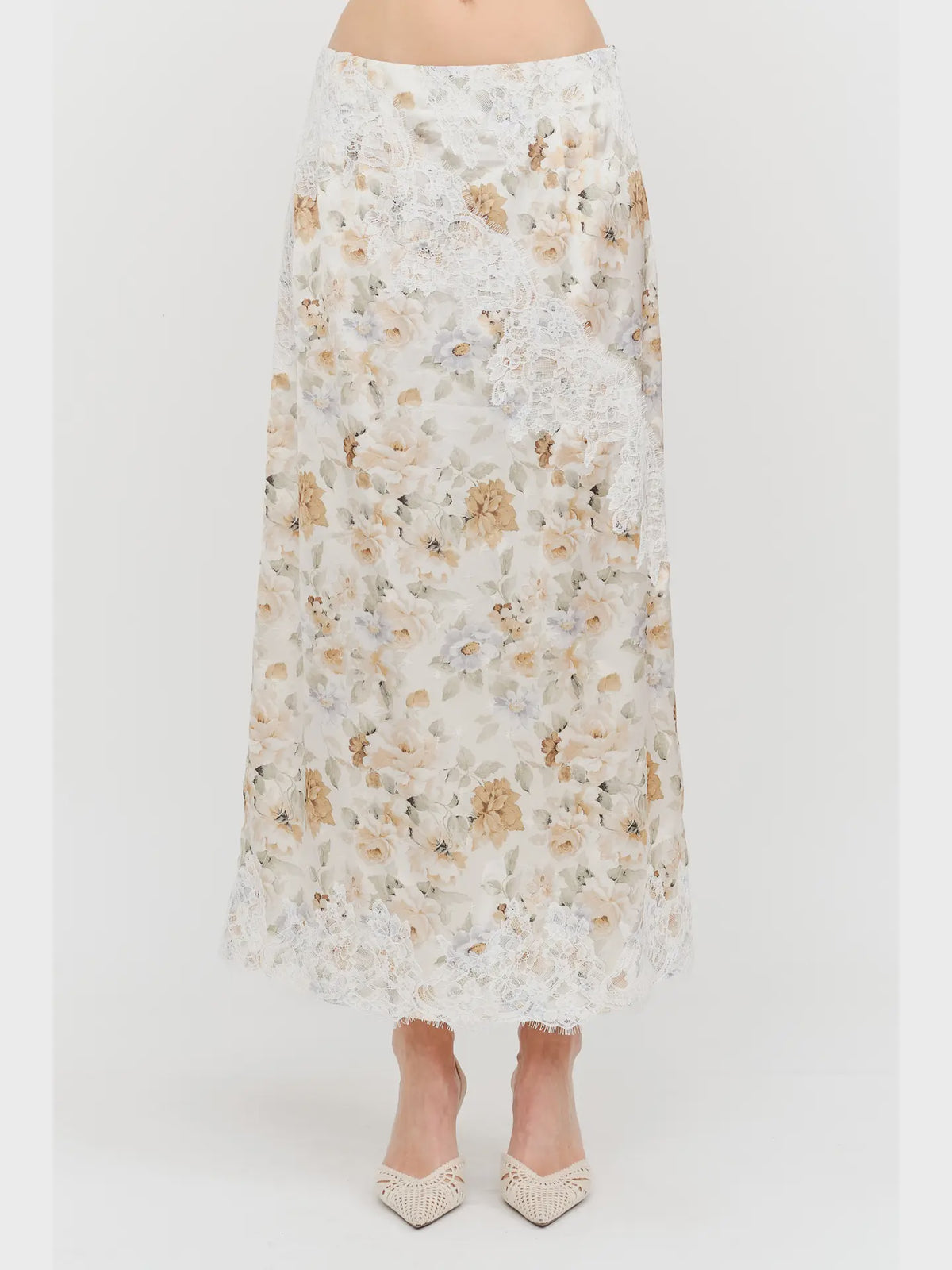 Harper Floral Midi Skirt in soft yellow and cream featuring a delicate floral print, smooth satin finish, white lace panel detailing, and a flowing midi-length silhouette.
