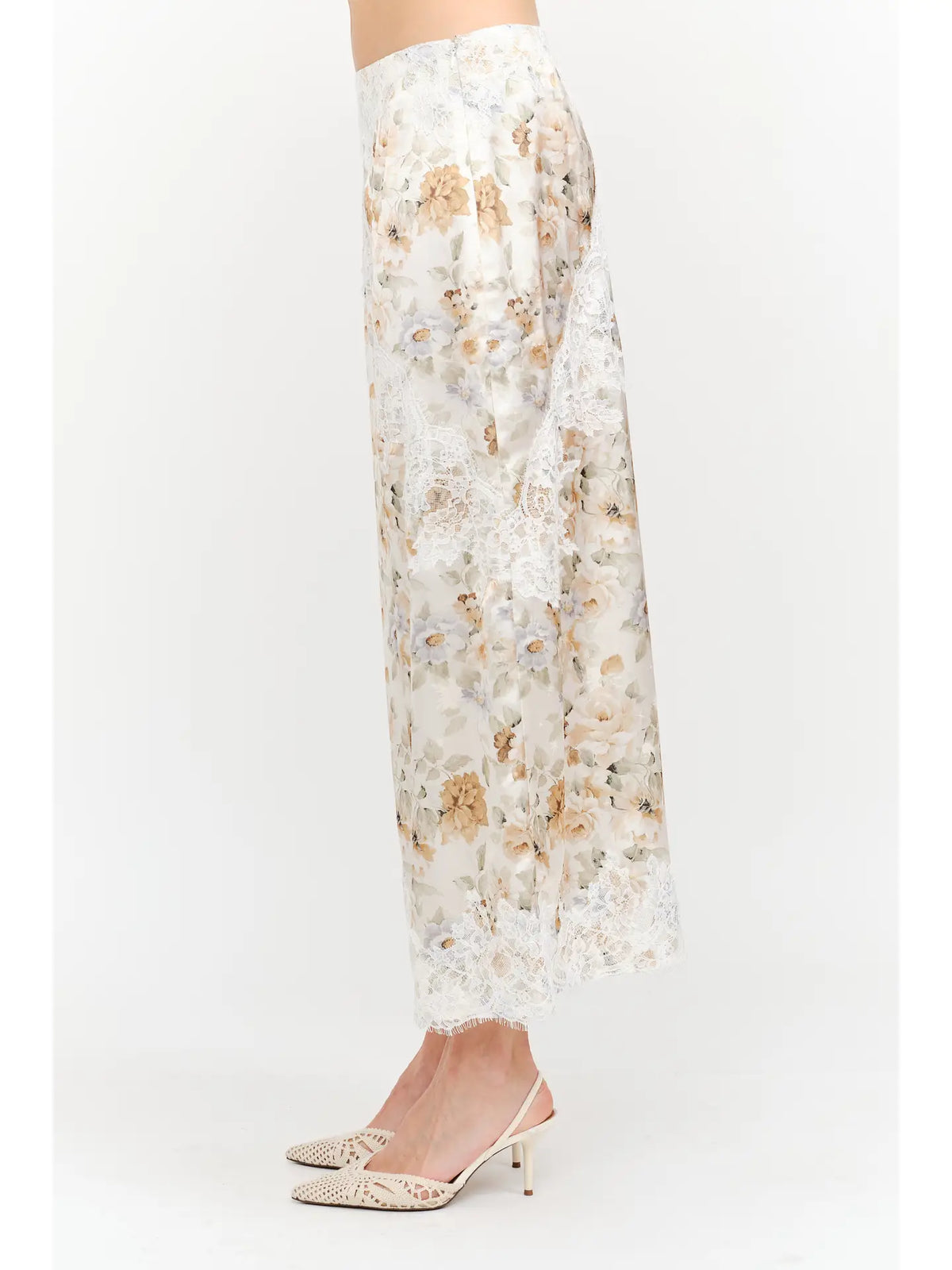 Harper Floral Midi Skirt in soft yellow and cream featuring a delicate floral print, smooth satin finish, white lace panel detailing, and a flowing midi-length silhouette.