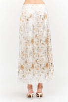 Harper Floral Midi Skirt in soft yellow and cream featuring a delicate floral print, smooth satin finish, white lace panel detailing, and a flowing midi-length silhouette.