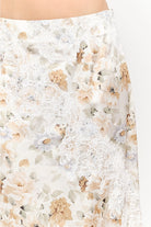 Harper Floral Midi Skirt in soft yellow and cream featuring a delicate floral print, smooth satin finish, white lace panel detailing, and a flowing midi-length silhouette.