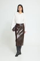 Brown High-waisted midi skirt featuring a straight silhouette, glossy textured finish, subtle panel stitching, and an exposed back zipper for a sleek, modern look.