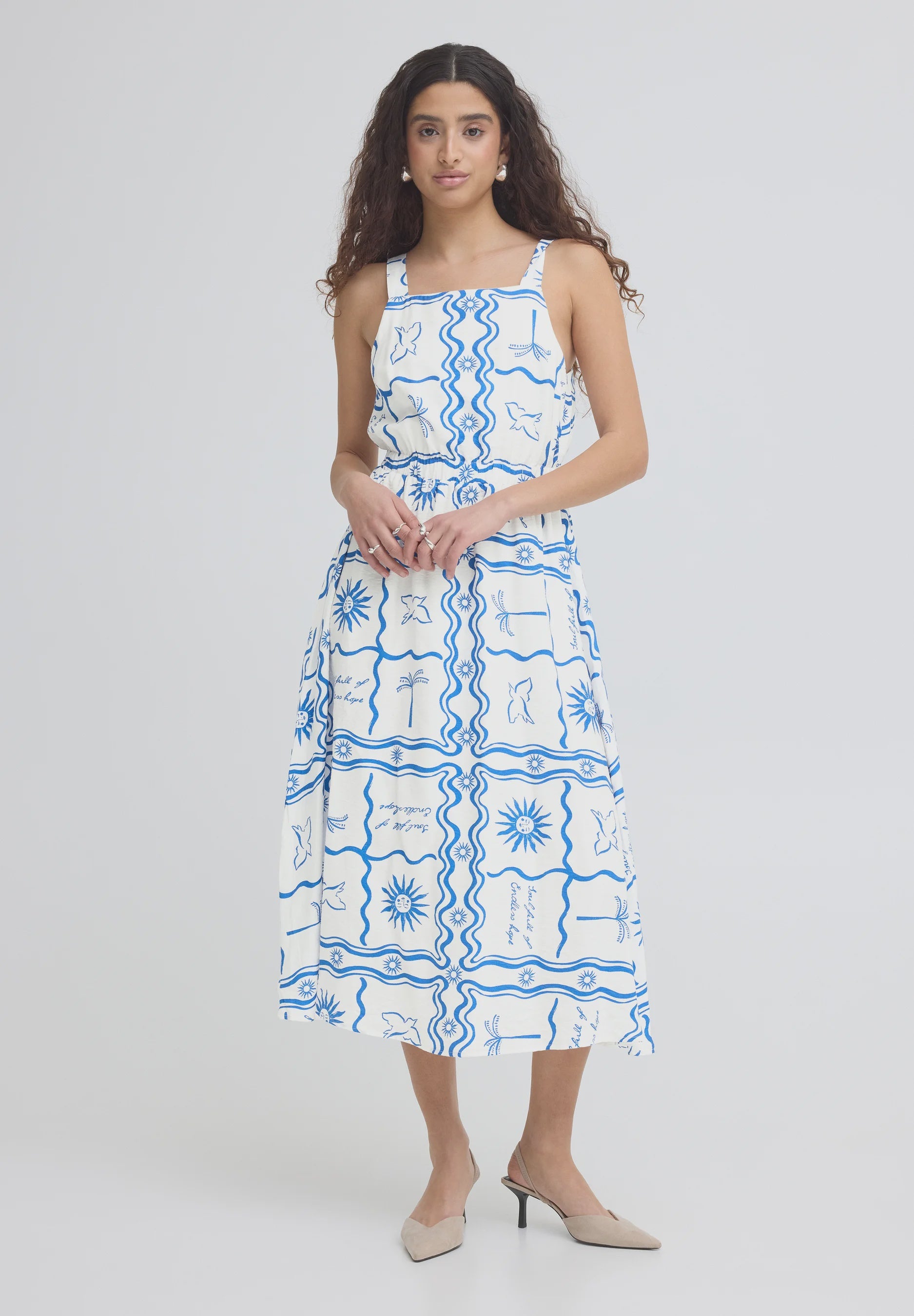 Woman wearing a white dress with blue patterns on a plain background