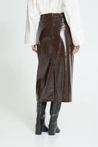 Brown High-waisted midi skirt featuring a straight silhouette, glossy textured finish, subtle panel stitching, and an exposed back zipper for a sleek, modern look.