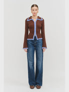 Model wearing the Jacquie Knit Top in brown, featuring a fitted silhouette, long sleeves, collared neckline, contrasting blue fuzzy trim, and two-way front zipper closure.