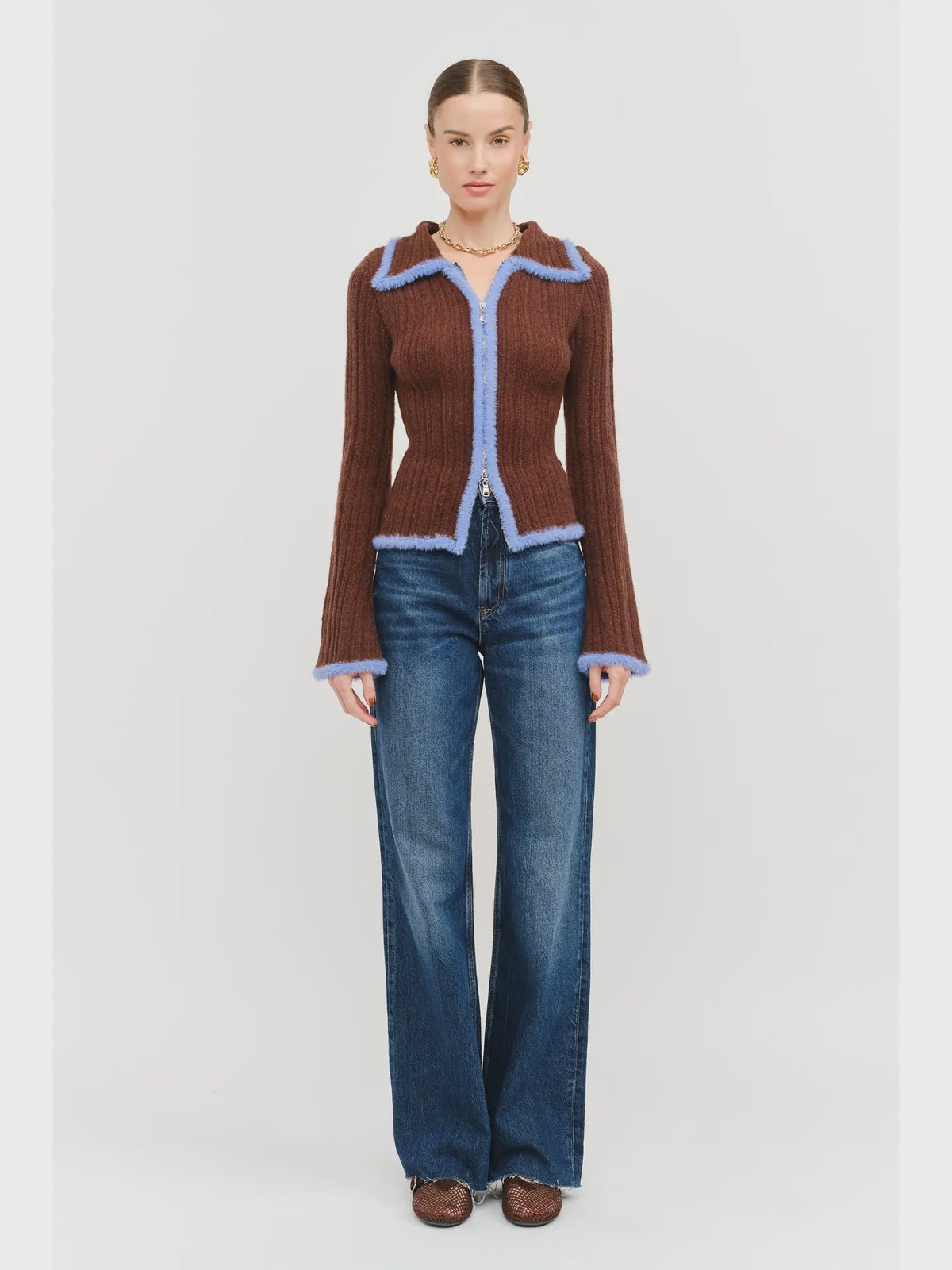 Model wearing the Jacquie Knit Top in brown, featuring a fitted silhouette, long sleeves, collared neckline, contrasting blue fuzzy trim, and two-way front zipper closure.