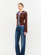 Model wearing the Jacquie Knit Top in brown, featuring a fitted silhouette, long sleeves, collared neckline, contrasting blue fuzzy trim, and two-way front zipper closure.