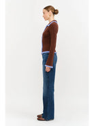 Model wearing the Jacquie Knit Top in brown, featuring a fitted silhouette, long sleeves, collared neckline, contrasting blue fuzzy trim, and two-way front zipper closure.