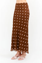 Kalila Midi Skirt in rich brown featuring soft pink polka dots, a flattering mermaid silhouette, and a flowing ankle-grazing hem.